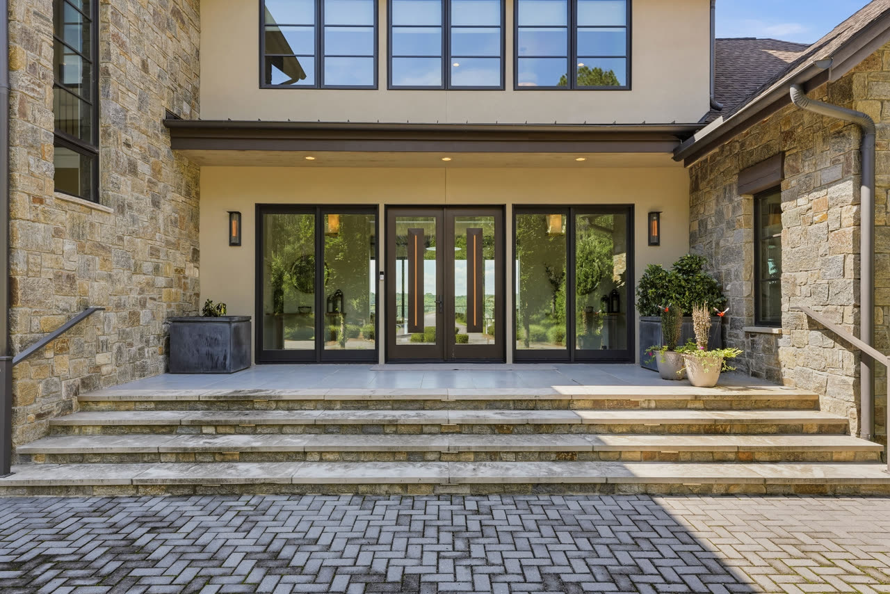 The front steps and the glass entry doors, seen from the paver courtyard.