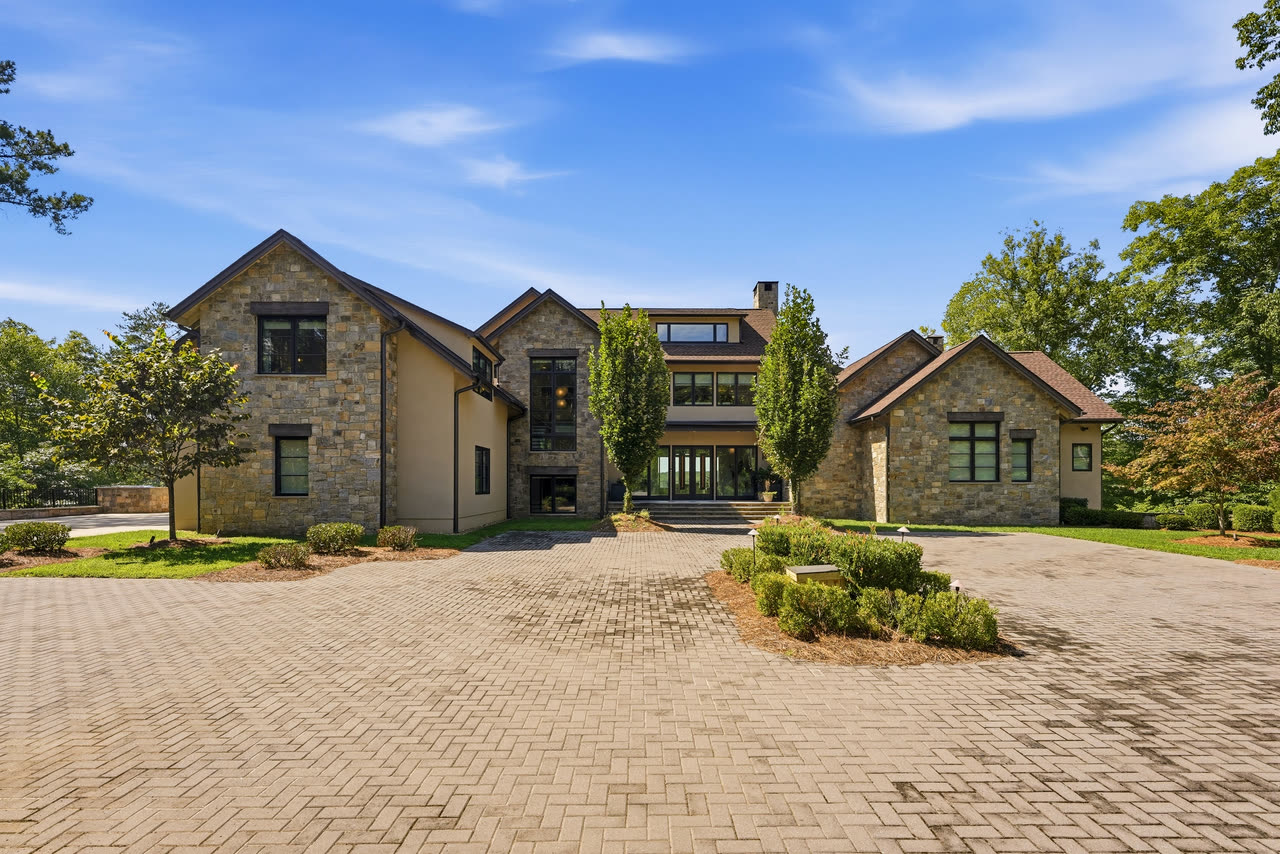 The front of the house straight on from the courtyard, three gables and a paver drive.