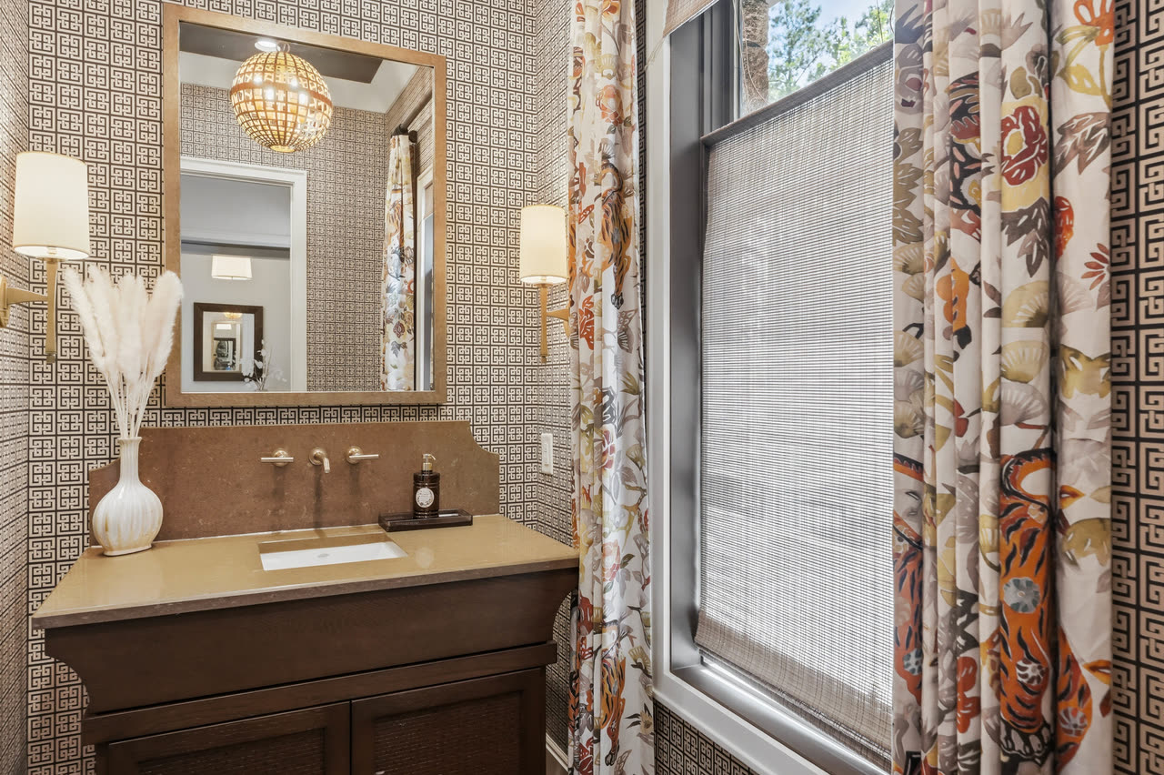 A powder room with patterned wallpaper and a wood vanity.