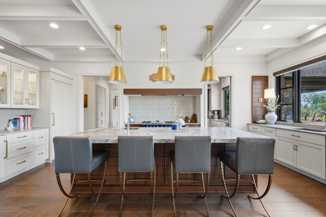 The kitchen island with bar stools, the range and hood behind it.