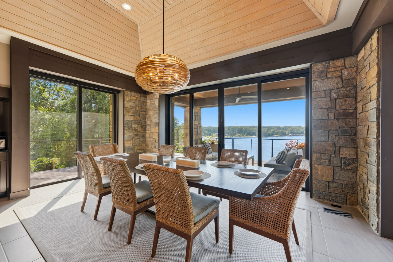 The screened dining porch with the lake through the retracted glass doors.