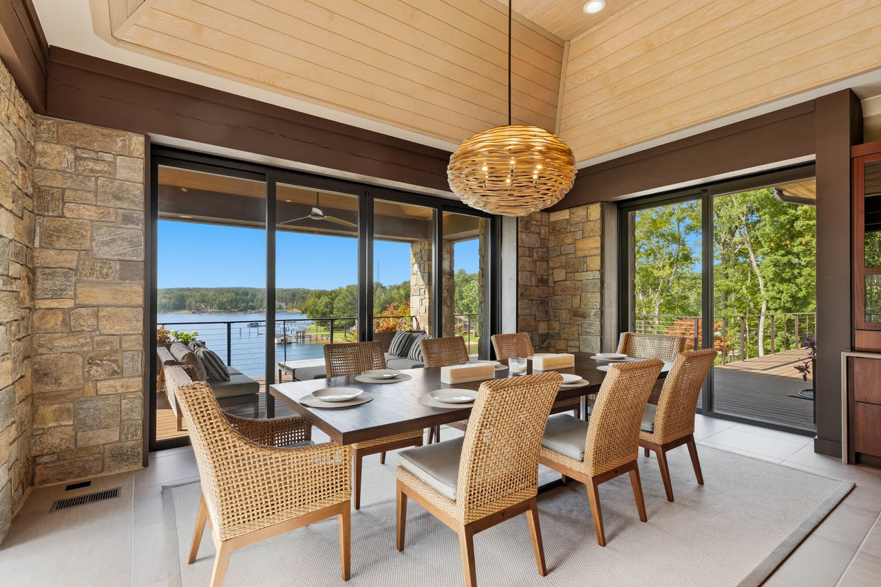 The dining porch table under a woven pendant, open to the water.