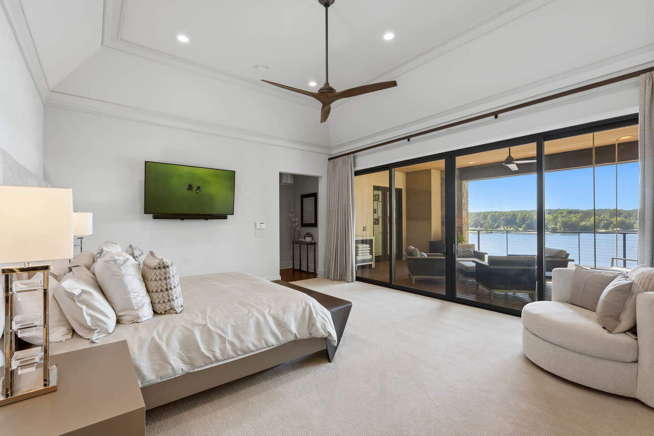 The primary bedroom, sliding doors open to the deck and the lake.