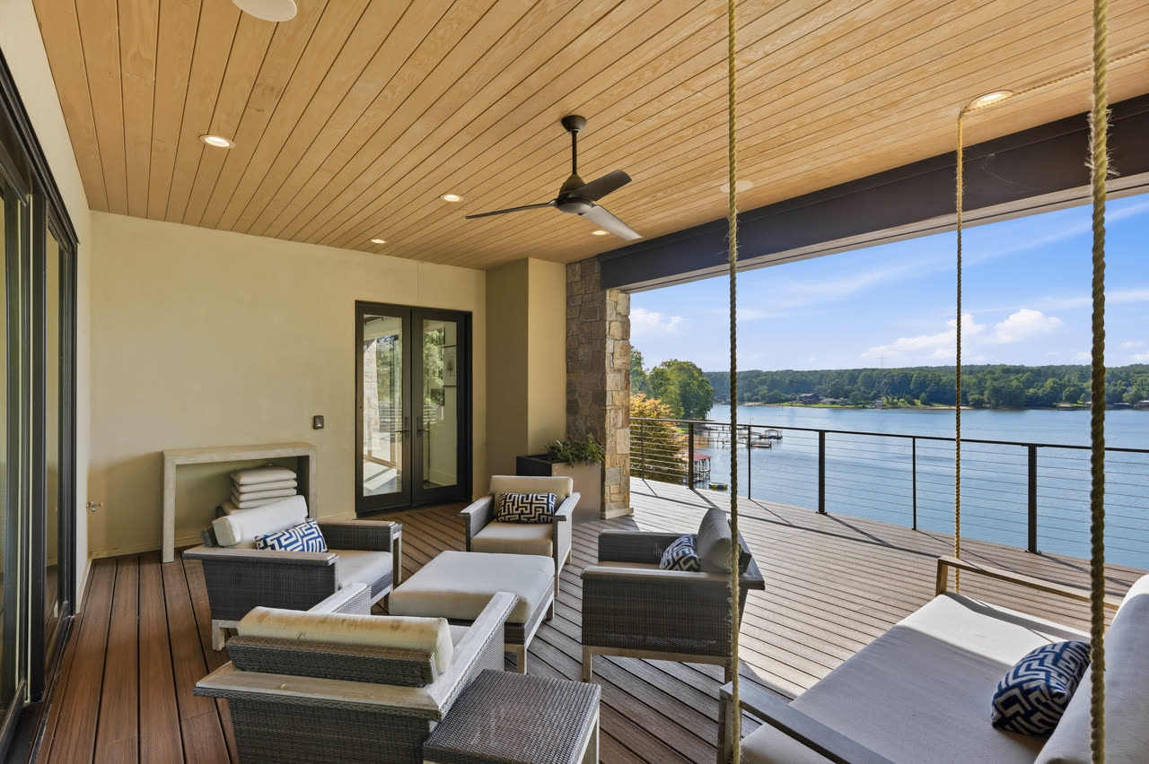 A covered porch of stone and timber looking out over the lake.