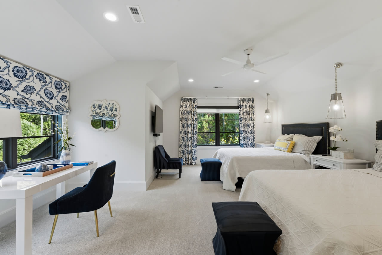 A guest bedroom with two beds and a desk under the window.