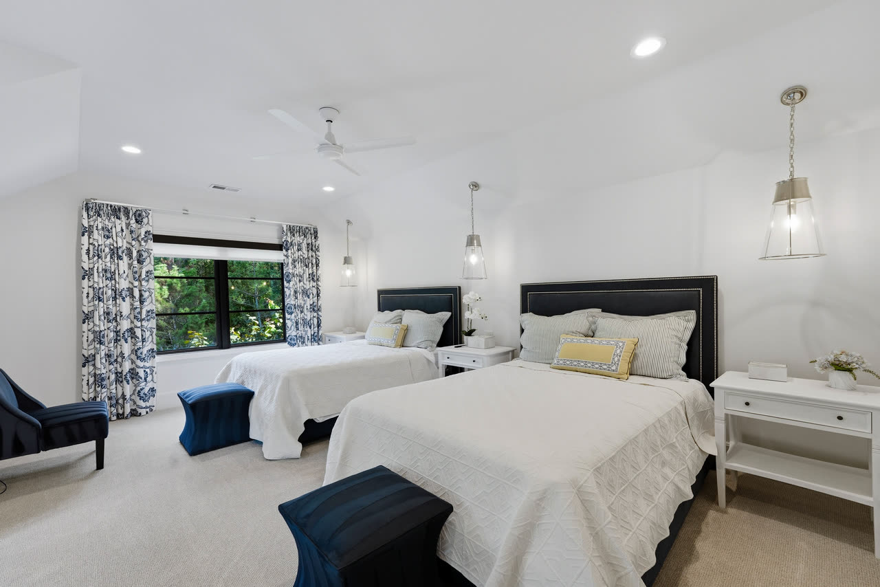 A guest bedroom with two beds and a bench at the foot of each.