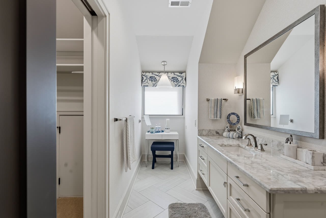 A guest bathroom vanity with the hall and the bedroom beyond.
