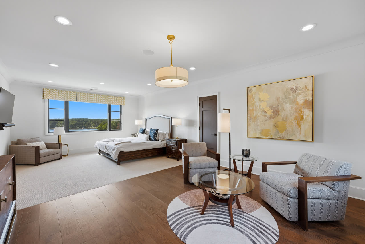 A guest bedroom with a seating area and a view down the lake.