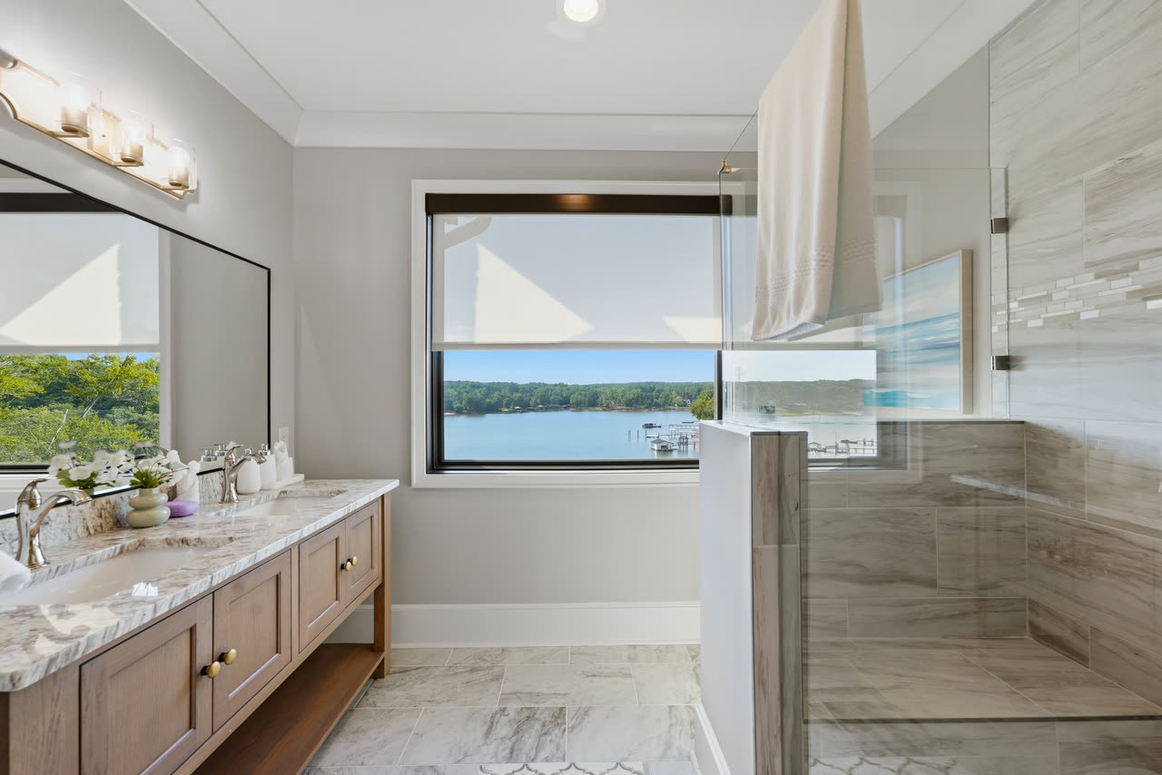 A guest bathroom with a double vanity and the lake through the window.