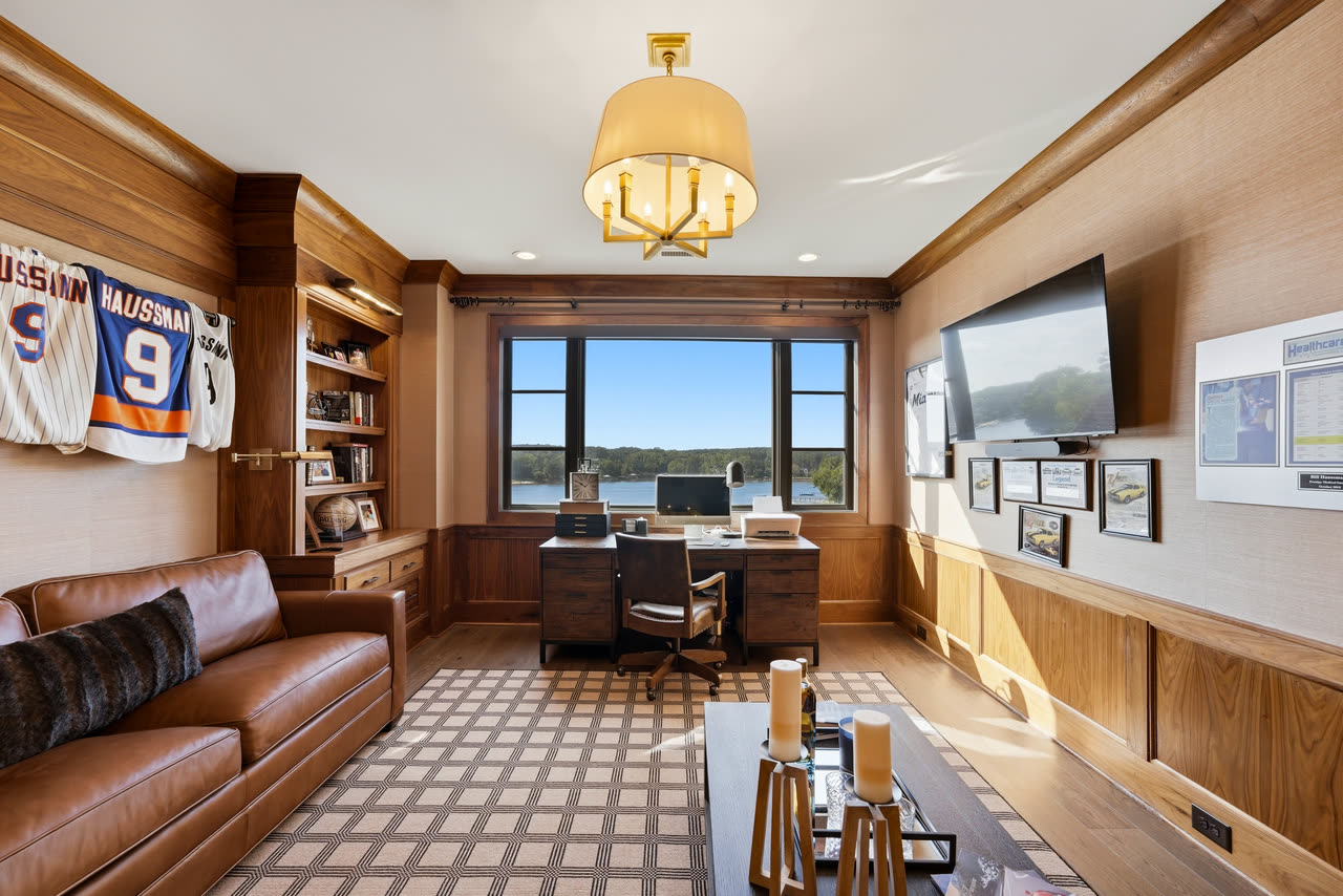 The wood panelled office, framed jerseys on the walls and the lake outside.