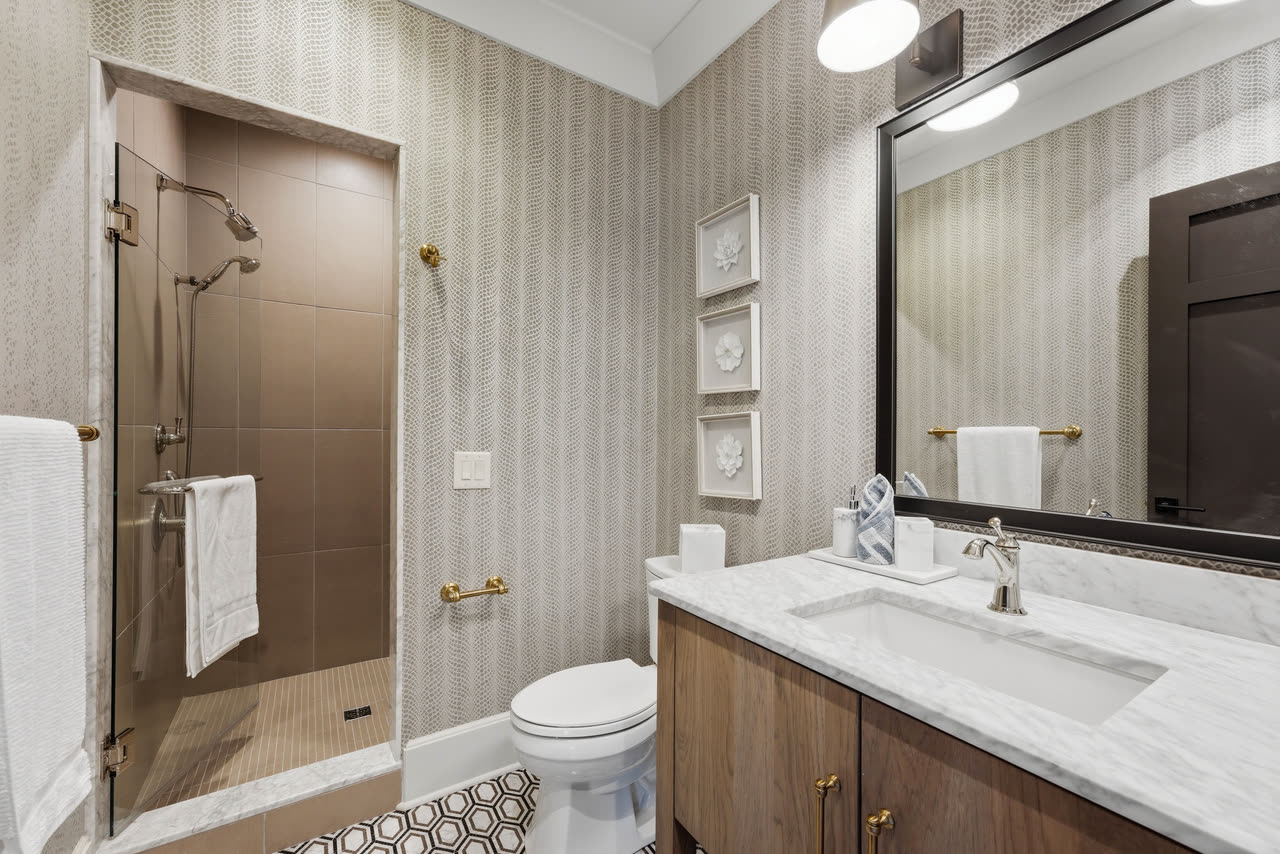 A guest bathroom with a tiled shower and a marble vanity.