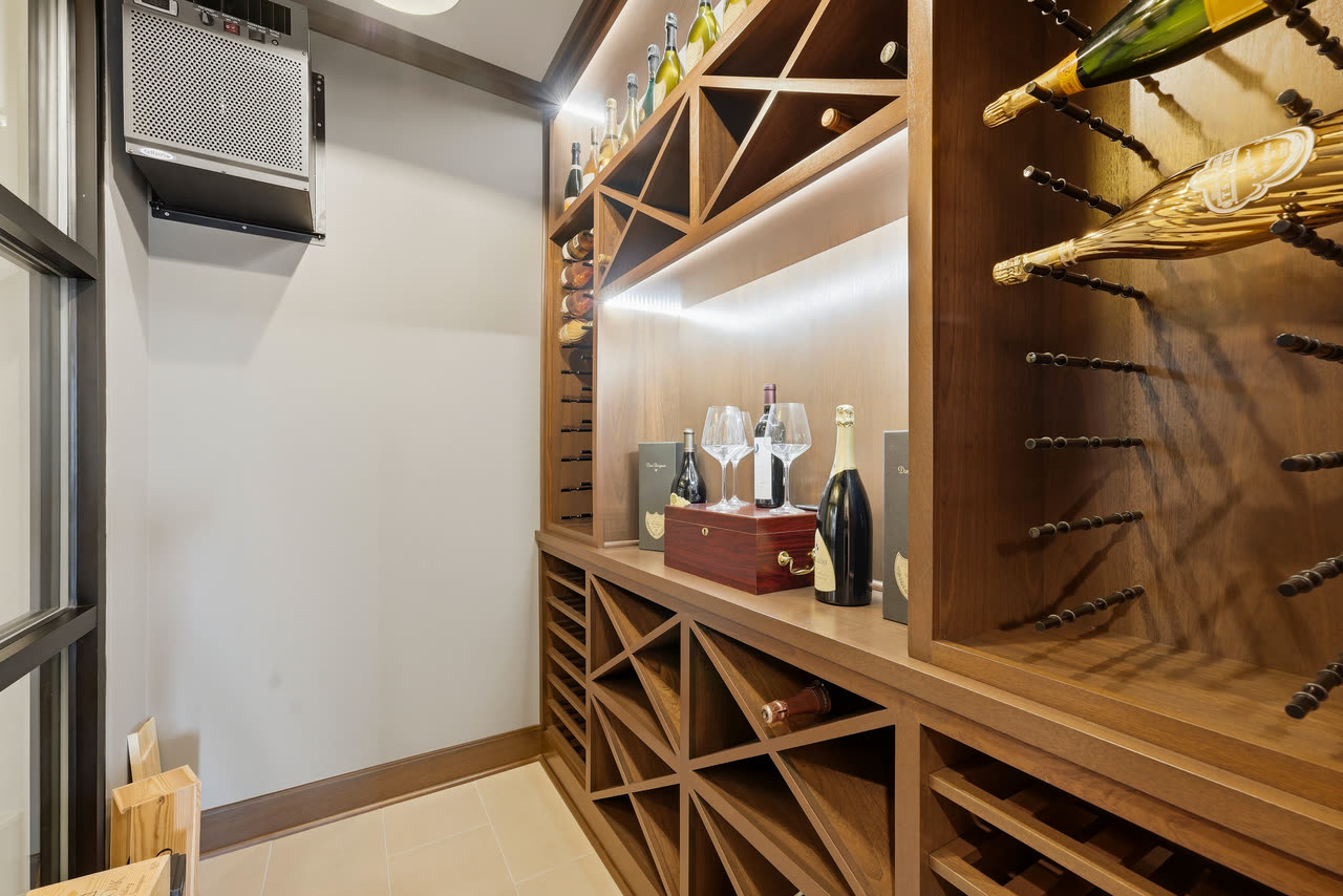 The wine cellar, timber racks and bottles under a lit shelf.