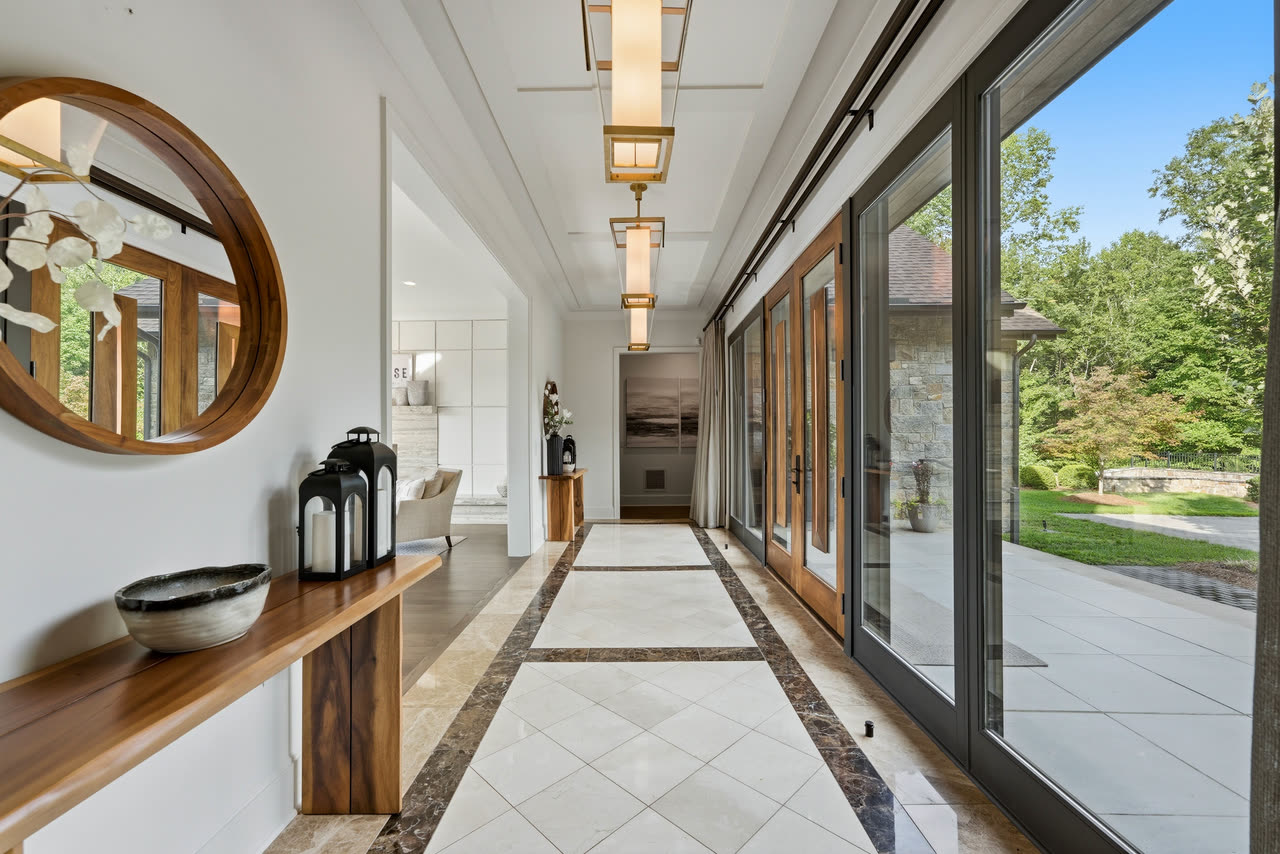 The gallery hall, a wall of glass on one side and a round mirror on the other.