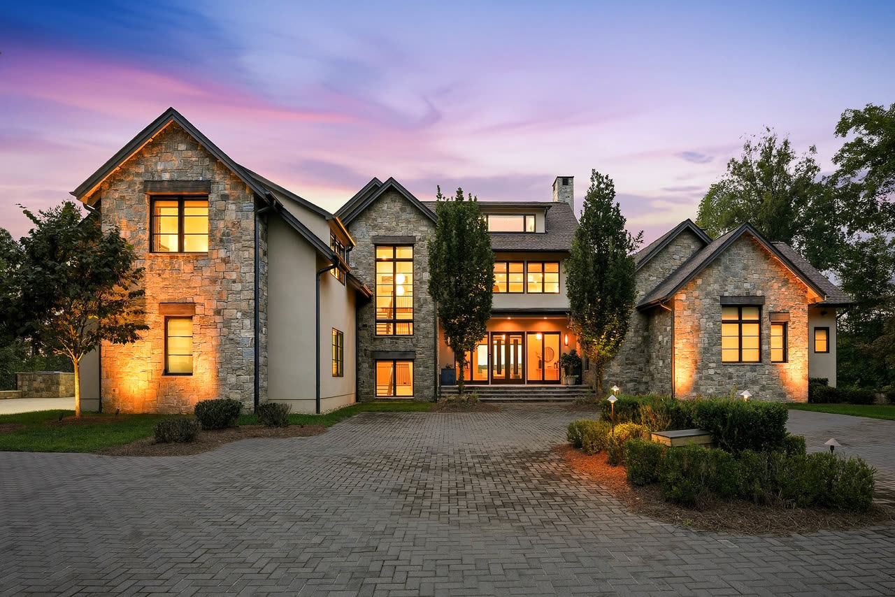 The front of the house at twilight, the windows lit and the doors closed.