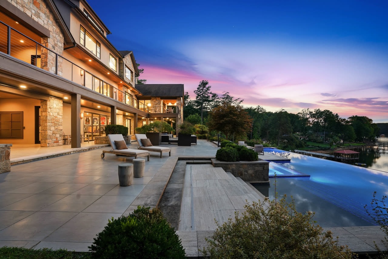 The rear terrace at twilight, the pool lit above the lake.
