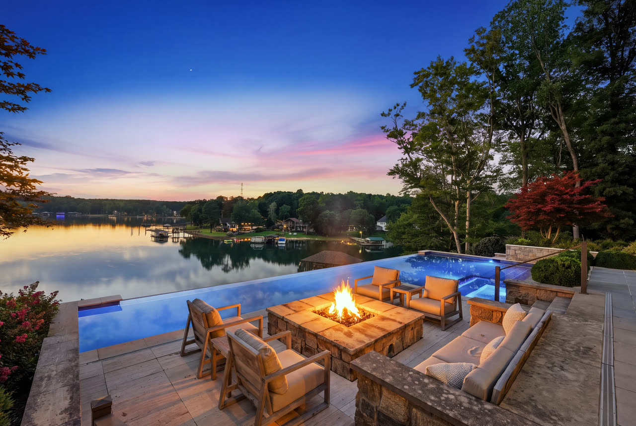 The fire pit alight at twilight, the lake and the sunset behind it.