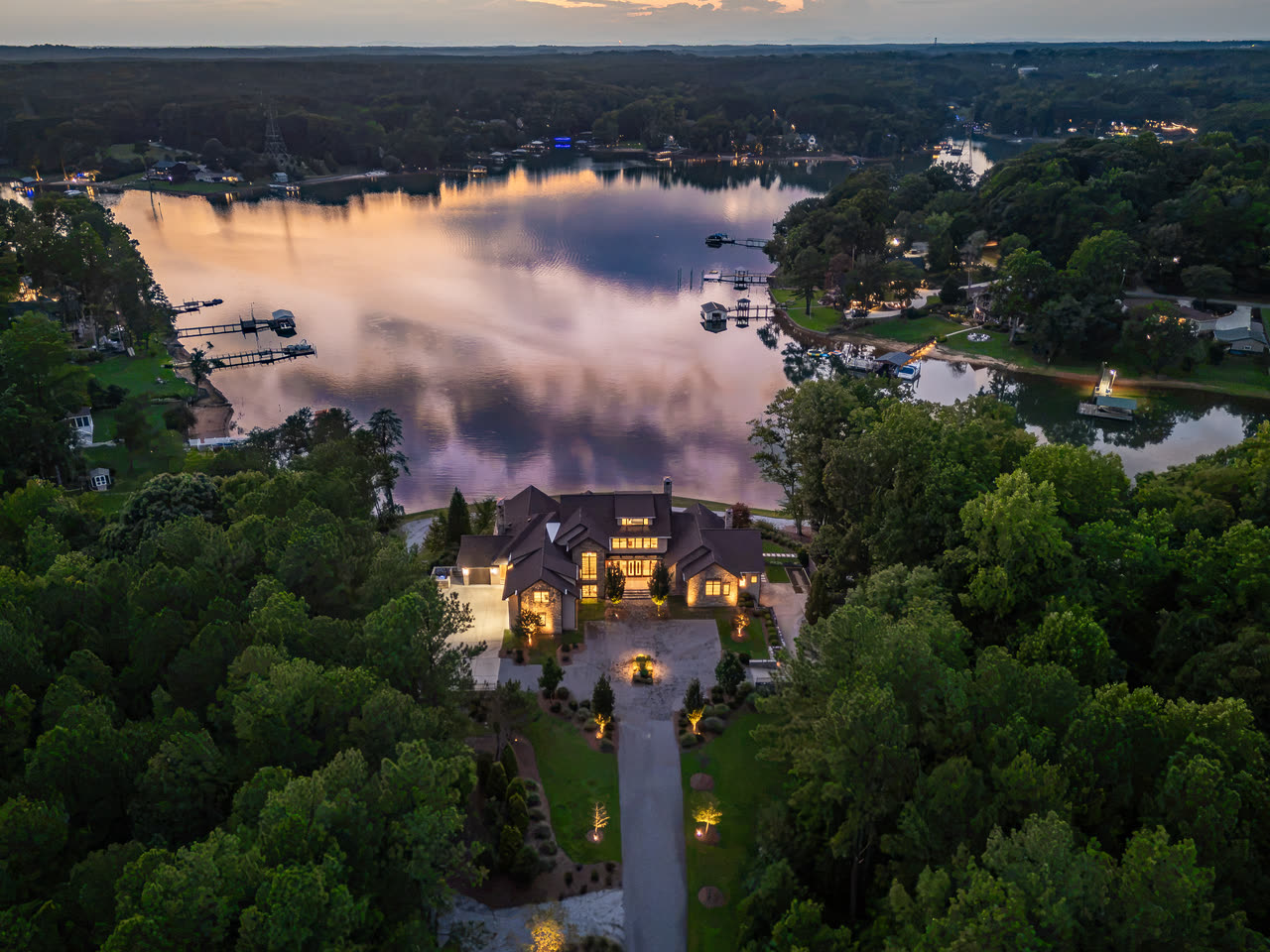 Aerial view of the lit house at twilight, the pool blue below it.