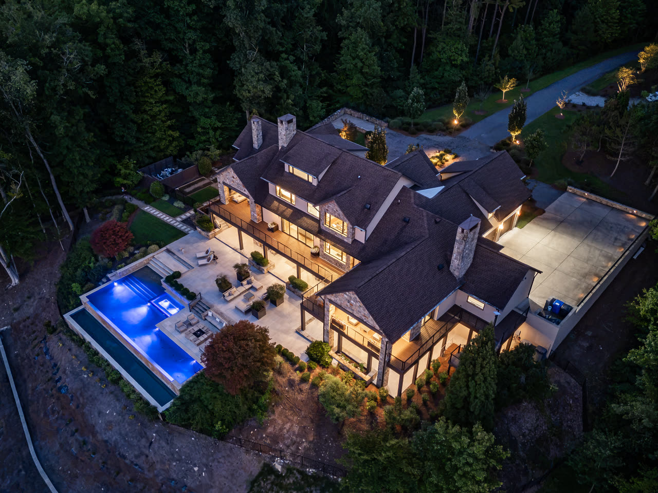 Aerial view straight down on the house, pool and shoreline at twilight.